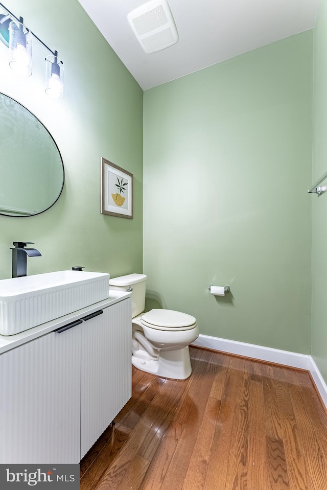 bathroom with visible vents, vanity, wood finished floors, toilet, and baseboards