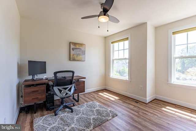 office space featuring baseboards, ceiling fan, wood finished floors, and visible vents