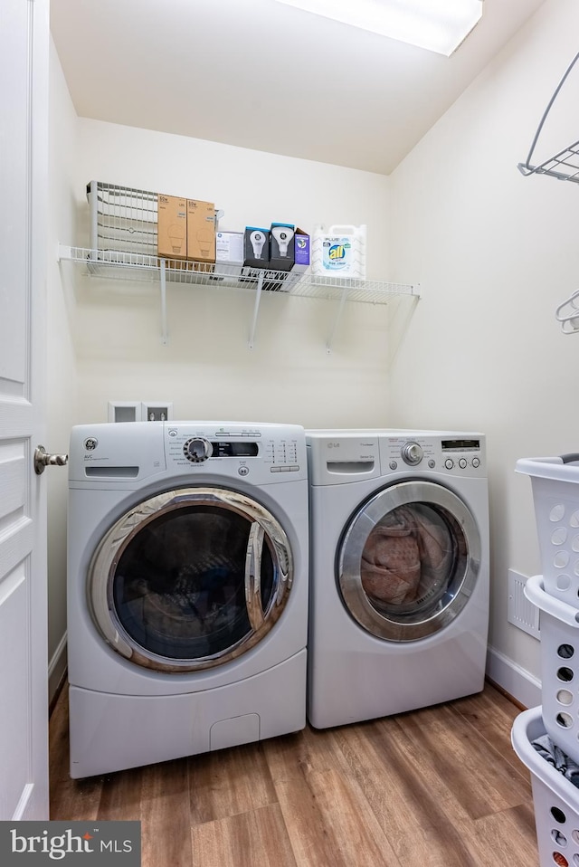 laundry room featuring washing machine and clothes dryer, laundry area, and wood finished floors