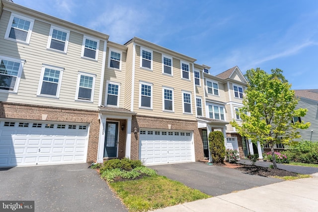 multi unit property with brick siding, driveway, and a garage