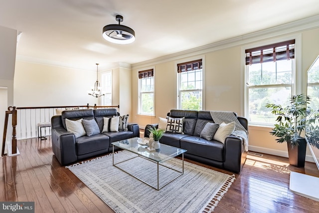living area with ornamental molding, a chandelier, dark wood-style floors, and a wealth of natural light