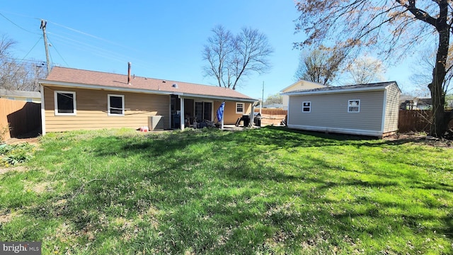 rear view of property featuring a fenced backyard, an outbuilding, and a lawn