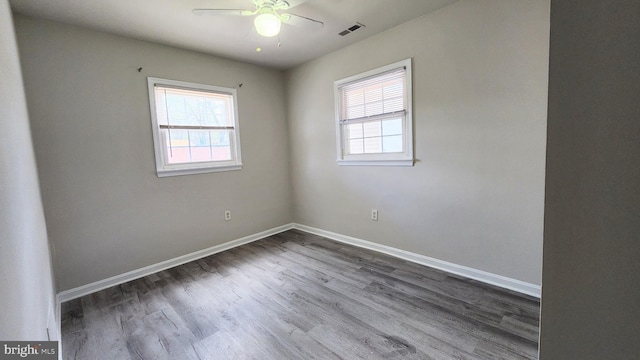 unfurnished room with dark wood finished floors, visible vents, a ceiling fan, and a healthy amount of sunlight