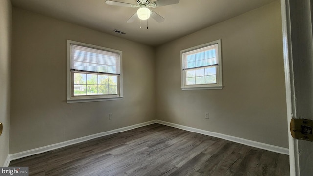 empty room featuring baseboards, a ceiling fan, dark wood-type flooring, and visible vents