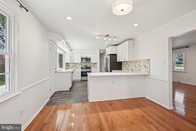 kitchen with appliances with stainless steel finishes, decorative backsplash, hardwood / wood-style flooring, and light countertops
