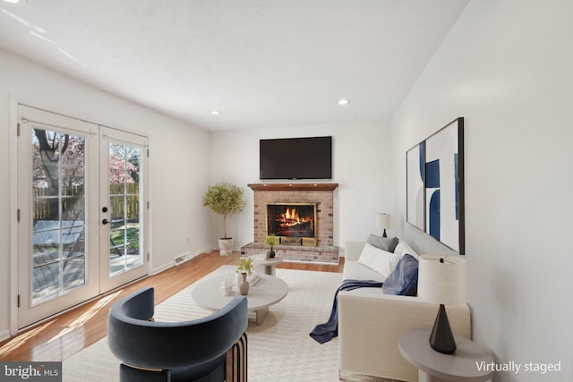 living area featuring a fireplace, wood finished floors, french doors, and visible vents
