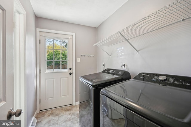 clothes washing area featuring independent washer and dryer, laundry area, and baseboards