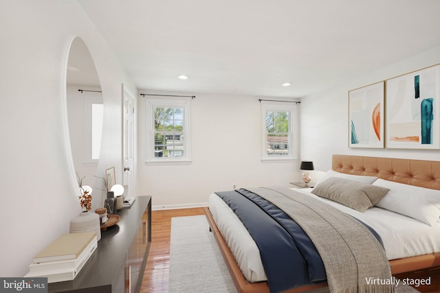bedroom featuring baseboards, recessed lighting, wood finished floors, and arched walkways