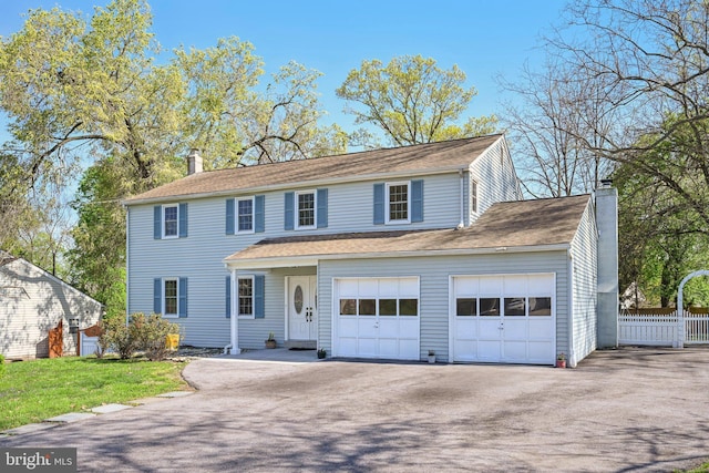 view of front of home featuring a chimney, fence, aphalt driveway, and a garage