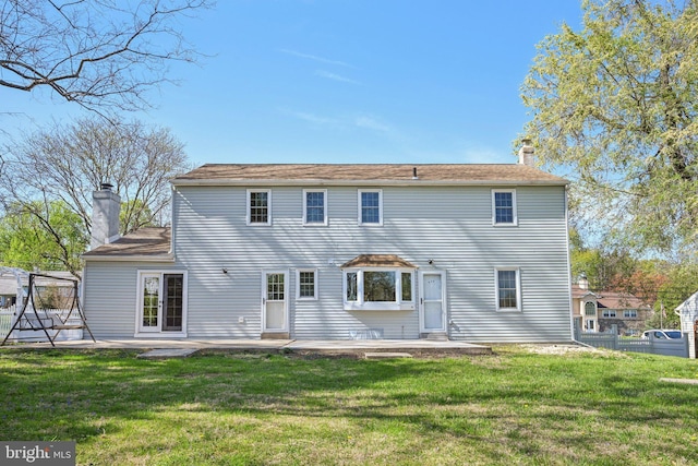 rear view of house with a lawn, a patio area, and a chimney