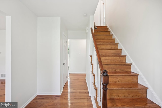 staircase featuring visible vents, wood finished floors, and baseboards
