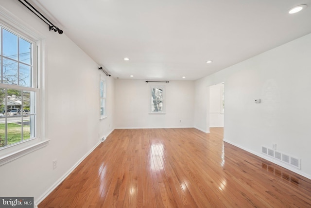 unfurnished living room featuring visible vents, baseboards, a wealth of natural light, and light wood-style floors