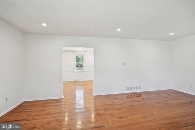 spare room featuring wood finished floors, visible vents, recessed lighting, and baseboards