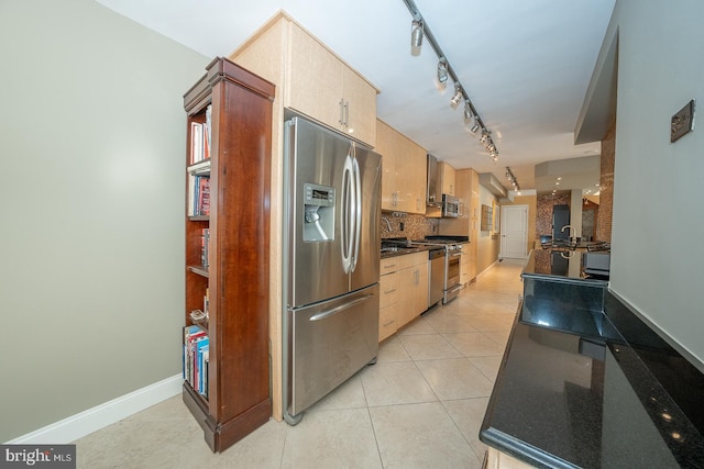 kitchen featuring dark countertops, tasteful backsplash, rail lighting, light tile patterned floors, and stainless steel appliances