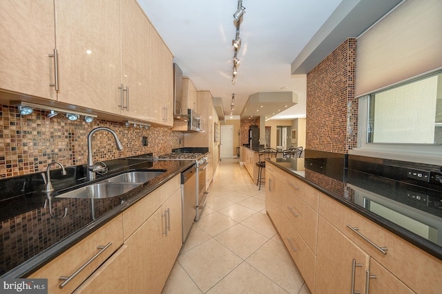 kitchen with a sink, dark stone countertops, light brown cabinetry, and decorative backsplash