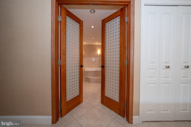 corridor featuring recessed lighting, baseboards, and light tile patterned floors