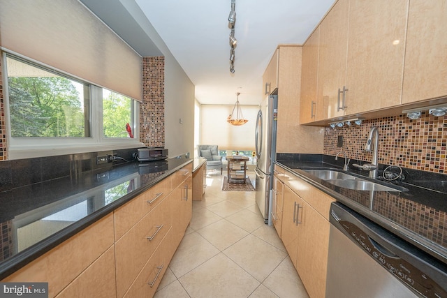 kitchen with a sink, tasteful backsplash, stainless steel appliances, and dark stone countertops
