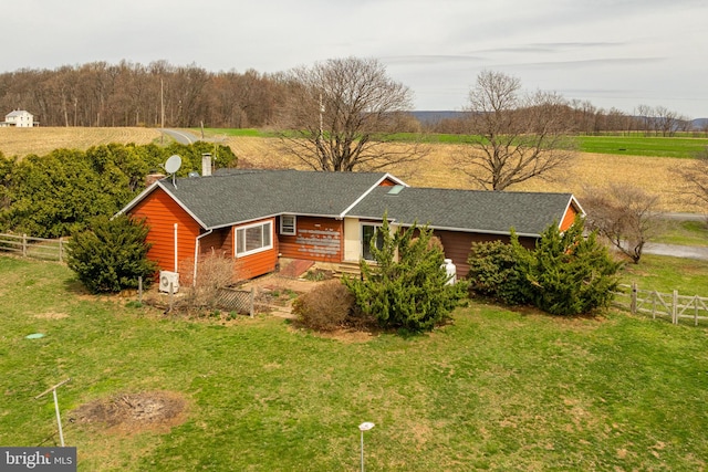 ranch-style house with roof with shingles, fence, and a front yard