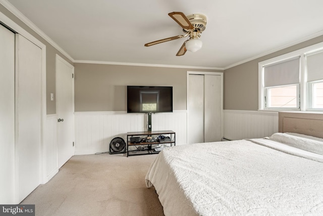 carpeted bedroom with a wainscoted wall, ornamental molding, a closet, and ceiling fan