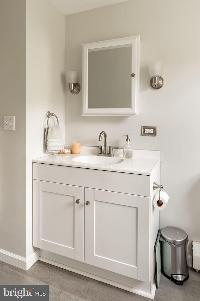 bathroom with baseboards, wood finished floors, and vanity