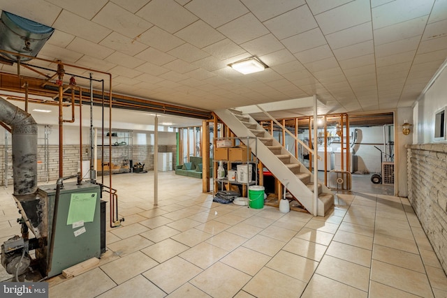 below grade area featuring stairs, a heating unit, tile patterned floors, and washer / clothes dryer