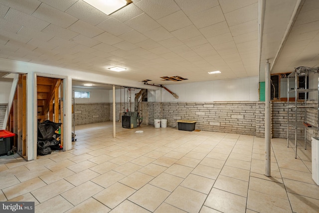 finished below grade area featuring stairs, brick wall, and a wainscoted wall