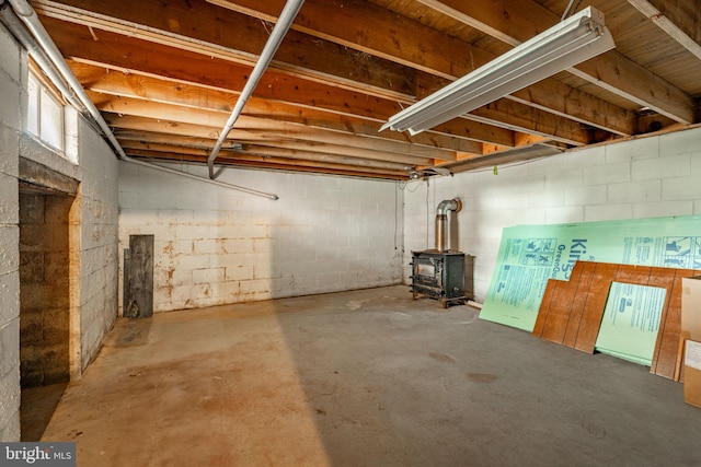 basement with concrete block wall and a wood stove