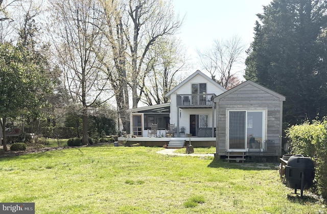 rear view of property featuring a sunroom, a yard, a balcony, and a deck