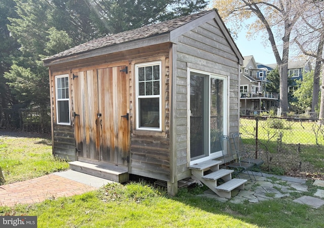 view of outbuilding with fence, an outdoor structure, and entry steps