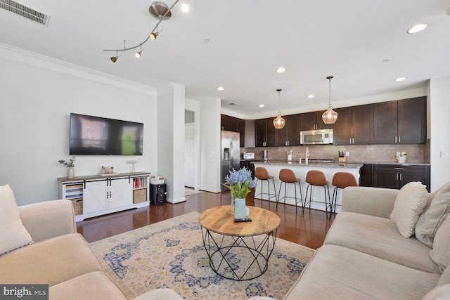 living area featuring visible vents, crown molding, baseboards, recessed lighting, and dark wood finished floors