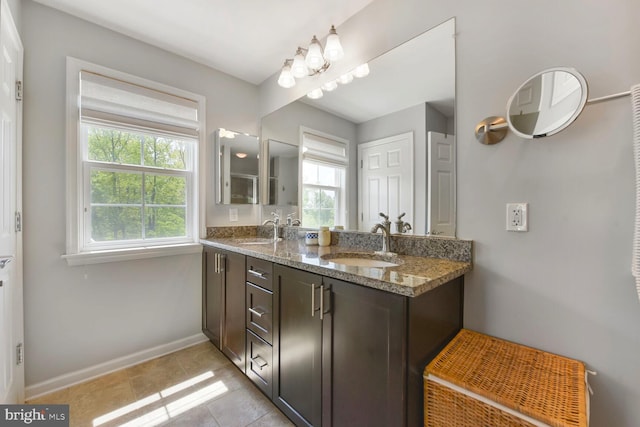 bathroom featuring a sink, baseboards, and a wealth of natural light