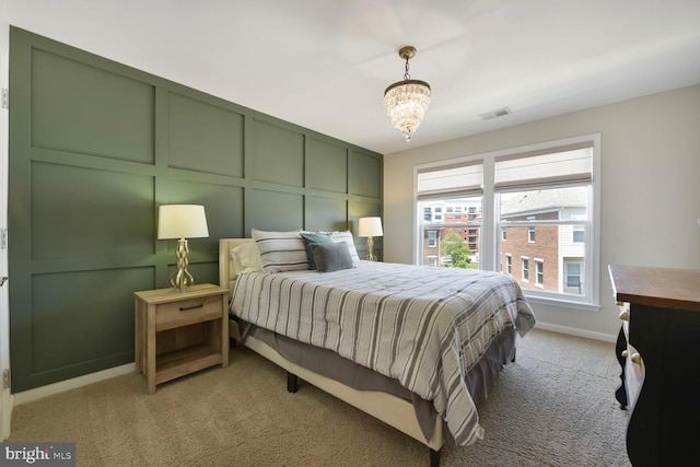bedroom featuring light colored carpet, a decorative wall, a chandelier, baseboards, and visible vents