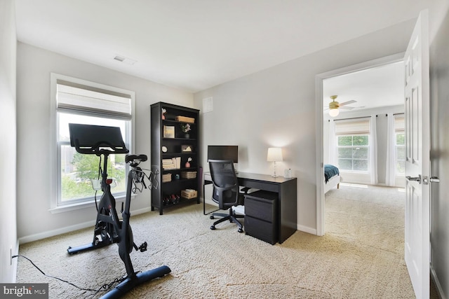 carpeted home office featuring a healthy amount of sunlight, baseboards, ceiling fan, and visible vents