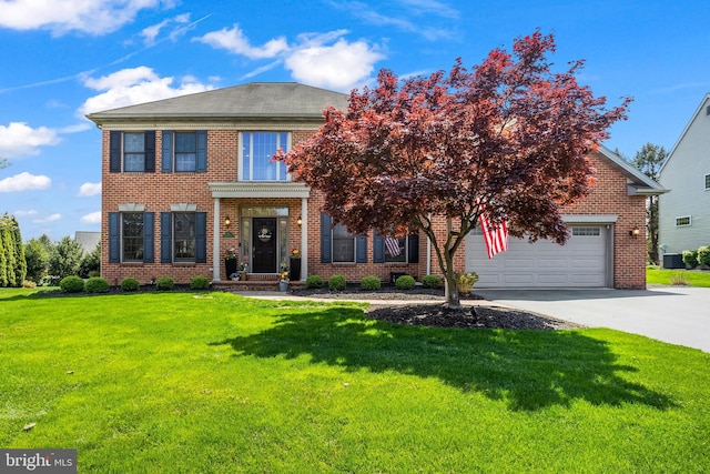 georgian-style home featuring driveway, a front lawn, brick siding, and a garage