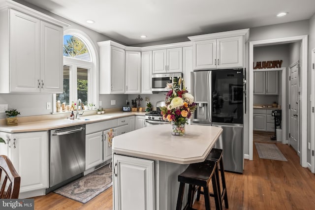 kitchen with light wood finished floors, a sink, white cabinetry, and stainless steel appliances