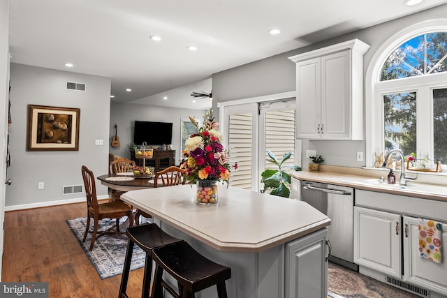 kitchen featuring visible vents, stainless steel dishwasher, a kitchen island, and light countertops