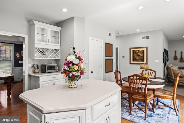 kitchen featuring wood finished floors, glass insert cabinets, a toaster, light countertops, and visible vents