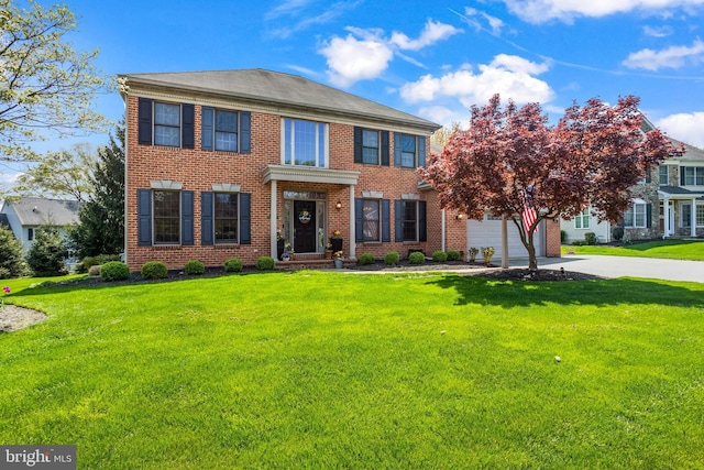 georgian-style home with concrete driveway, a front lawn, and brick siding
