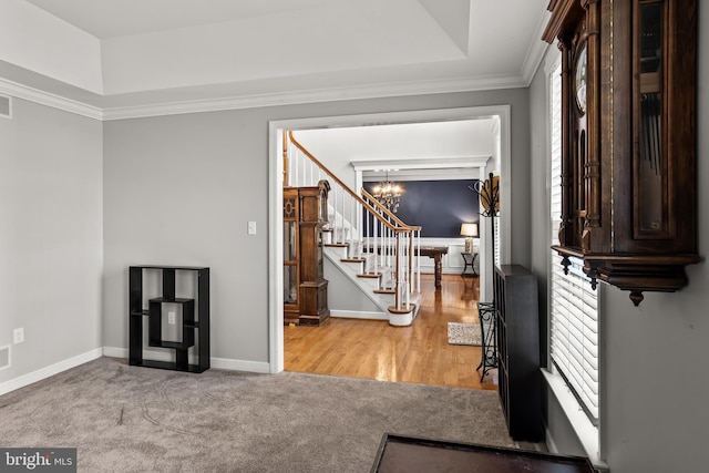 entrance foyer featuring carpet floors, baseboards, stairway, a notable chandelier, and crown molding