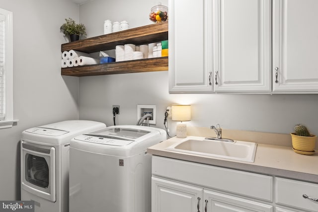 clothes washing area featuring washer and dryer, cabinet space, and a sink