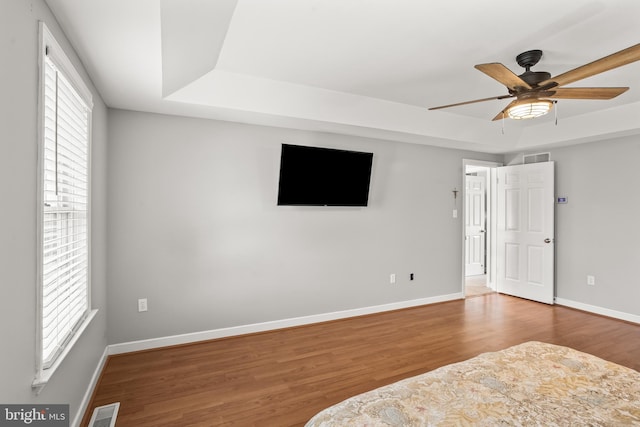 unfurnished bedroom with visible vents, ceiling fan, wood finished floors, and baseboards