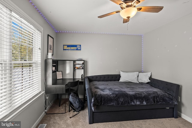 carpeted bedroom with multiple windows, ceiling fan, and baseboards