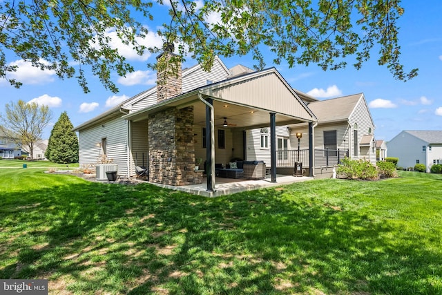 rear view of property featuring a lawn, a ceiling fan, a patio area, and stone siding