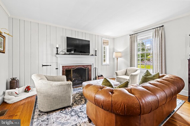 living room with ornamental molding, hardwood / wood-style floors, a fireplace, and baseboards