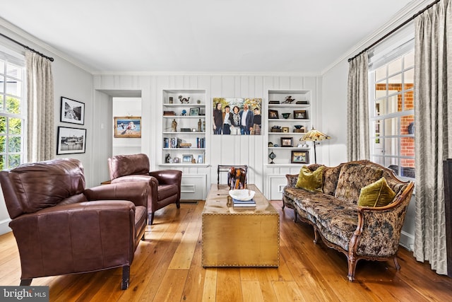 living area with crown molding, hardwood / wood-style floors, and built in features