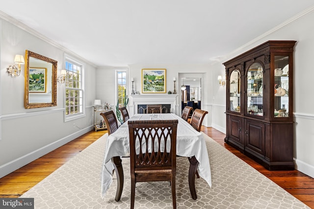 dining space with hardwood / wood-style flooring, ornamental molding, and baseboards
