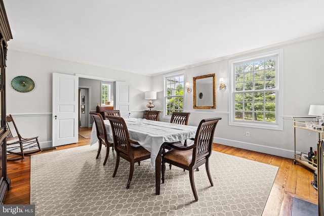dining room featuring crown molding, baseboards, and hardwood / wood-style flooring