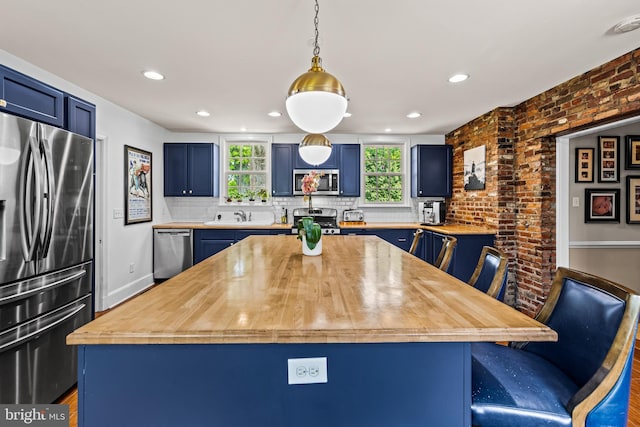 kitchen featuring stainless steel appliances, blue cabinetry, a center island, backsplash, and recessed lighting