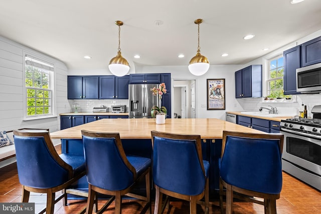 kitchen featuring appliances with stainless steel finishes, blue cabinetry, backsplash, and recessed lighting