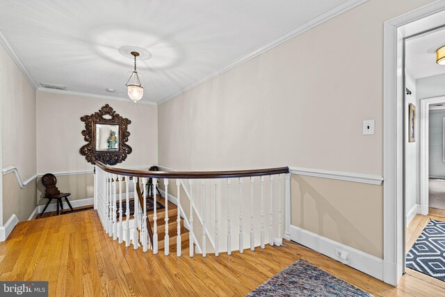 hallway with an upstairs landing, wood finished floors, baseboards, and crown molding